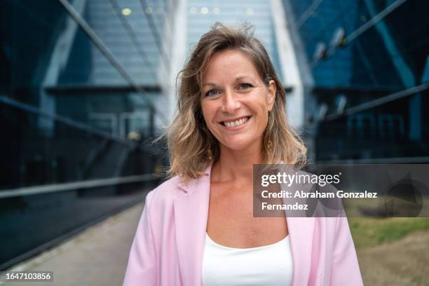 smiling blonde businesswoman standing next to a financial building - ceo stock pictures, royalty-free photos & images