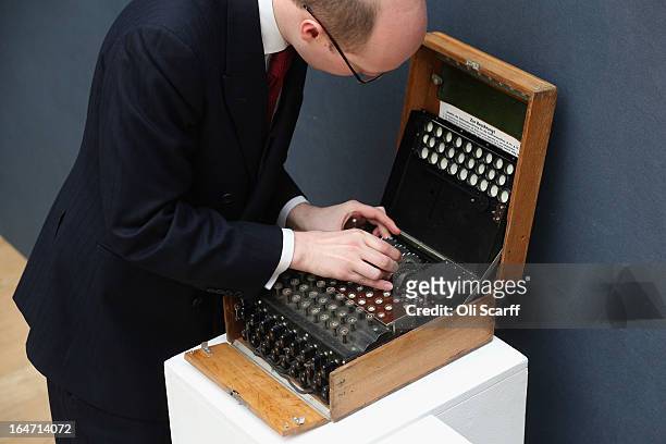 An employee at Christie's auction house examines an Enigma cipher machine on March 27, 2013 in London, England. The Enigma machine is expected to...