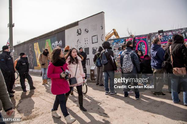 People gather as police stand guard next to a section of the Berlin Wall which has been removed to make way for a luxury apartments development on...
