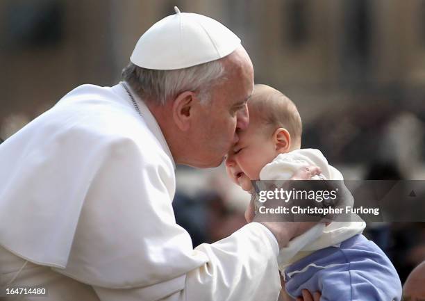 Pope Francis kisses a baby as he drives around St Peter's Square after his first weekly general audience as pope on March 27, 2013 in Vatican City,...