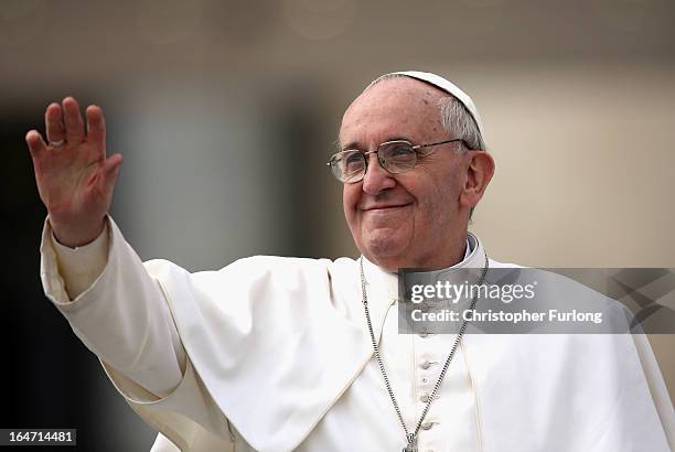 Pope Francis greets the crowd as he drives around St Peter's Square ahead of his first weekly general audience as pope on March 27, 2013 in Vatican...