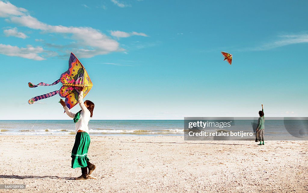 Madre e hija volando cometas en la playa