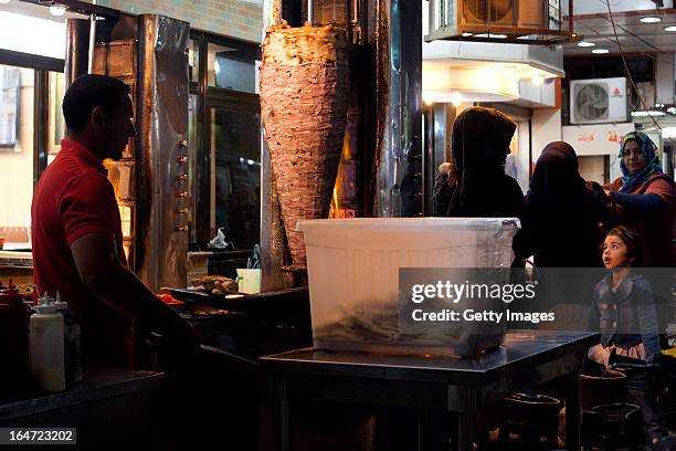 Young girl watches a street vendor making shwarma sandwiches, March 18, 2013 in Baghdad, Iraq. Ten years after the regime of Saddam Hussein was...