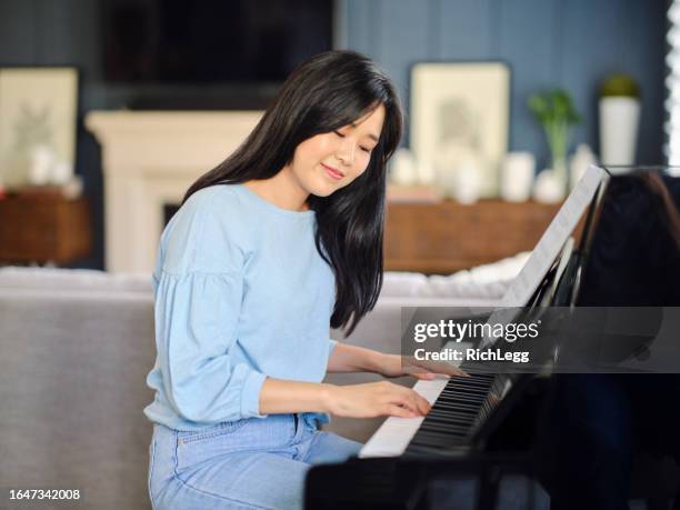 adult woman practicing piano in a home - pianist imagens e fotografias de stock