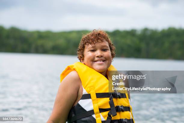 smiling boy in a life jacket at the lake - colete-salva-vidas imagens e fotografias de stock