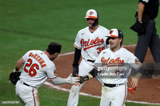 Adley Rutschman, Ryan McKenna and Gunnar Henderson of the Baltimore Orioles celebrate after scoring against the Chicago White Sox in the seventh...