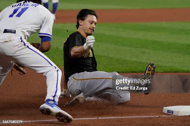 Bryan Reynolds of the Pittsburgh Pirates slides into third for a triple against Maikel Garcia of the Kansas City Royals in the eighth inning at...