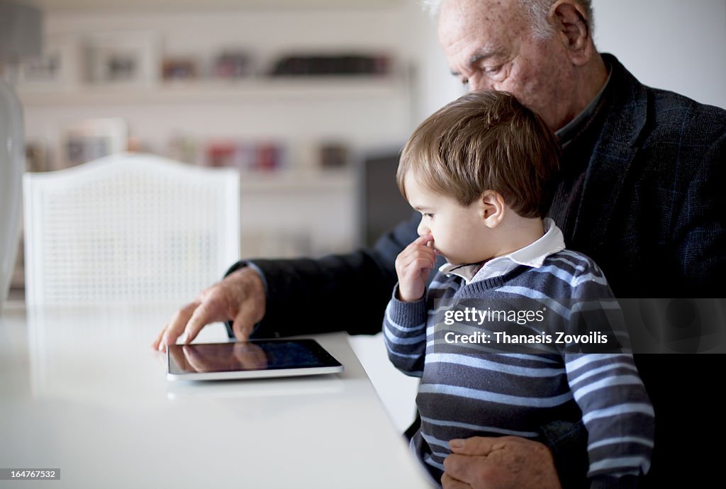 Grandfather with his grandson looking at a tablet