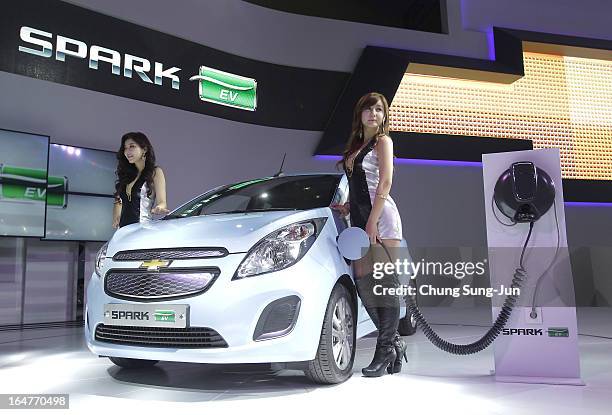 Models pose next to a Chevrolet Spark EV at the Seoul Motor Show 2013 on March 28, 2013 in Goyang, South Korea. The Seoul Motor Show 2013 will be...