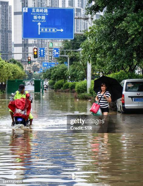 People wade through the water at a flooded area after heavy rains caused by Typhoon Haikui in Fuzhou, in China's southern Fujian province on...