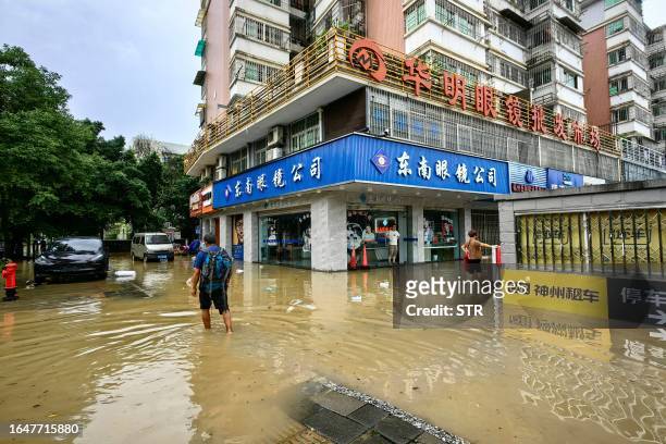 People wade through the water at a flooded area after heavy rains caused by Typhoon Haikui in Fuzhou, in China's southern Fujian province on...