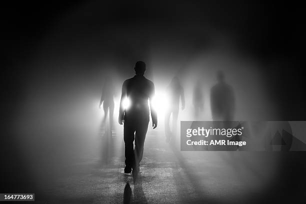 siluetas de personas caminando hacia la luz - muerte fotografías e imágenes de stock