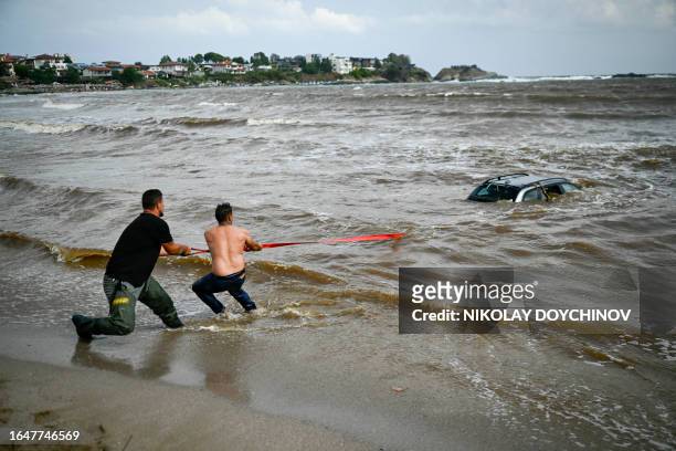 People try to pull out a car submerged in the sea at Arapia camping site near Tsarevo along the Bulgarian Black sea coast, on September 6, 2023. The...
