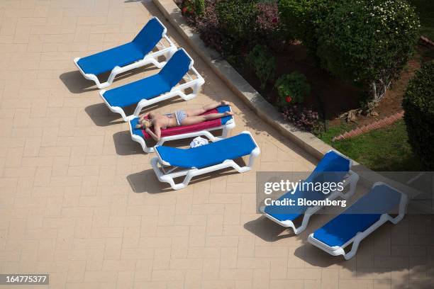Woman bathes in the sun at the poolside at the luxury five star St Raphael resort hotel in Limassol, Cyprus, on Wednesday, March 27, 2013. Directly...