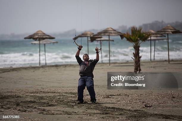 Man holds onto his kite in high winds on a deserted beach in Limassol, Cyprus, on Wednesday, March 27, 2013. The ECB said on March 25 it won't stop...