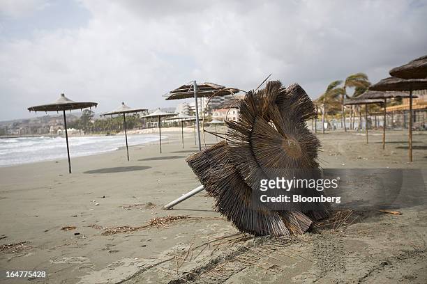 Straw parasol lies disused after being blown over by high wind on the beach in Limassol, Cyprus, on Wednesday, March 27, 2013. The ECB said on March...