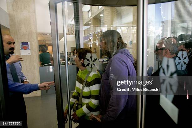 People pile through a revolving door at a branch of Laiki Bank as the country's banks re-open following 12 days of closure on March 28, 2013 in...