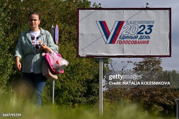 Woman walks in front of a billboard announcing the upcoming three-day local elections across Russia and in Russian-controlled regions of Ukraine...