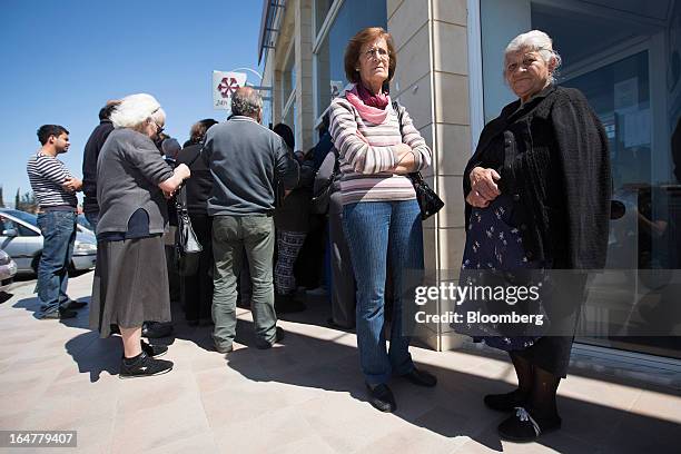 Customers wait to enter a branch of the Cyprus Popular Bank Pcl, also known as Laiki Bank, as it opens for the first time in two weeks in Nicosia,...