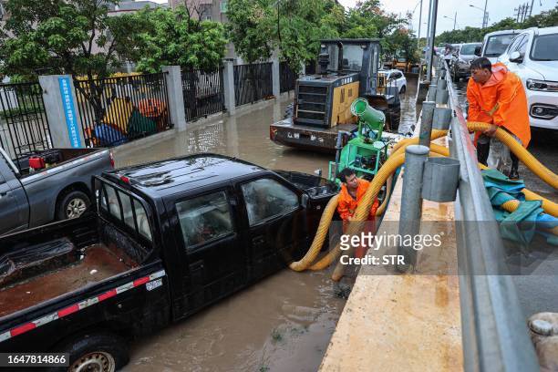 Workers use a pump to drain water at a flooded area following heavy rains caused by Typhoon Haikui in Xiamen, in China's southern Fujian province on...