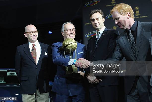 Volkswagen design chief Walter de Silva holds a trophy while being congratulated for the Volkswagen Golf being named the 2013 World Car of the Year...