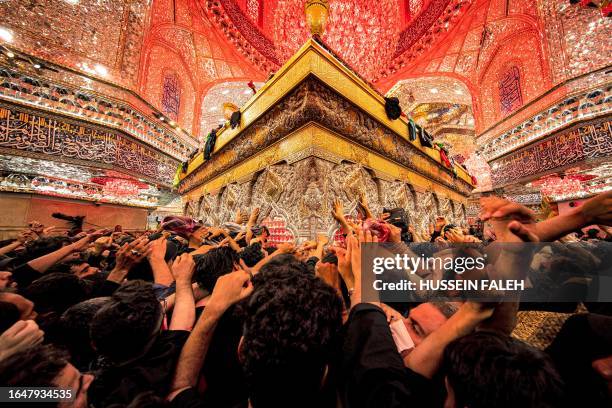 Shiite Muslim devotees reach to receive a blessing from the tomb of Imam Hussein, the Prophet Mohammed's grandson, at the Imam's shrine in Iraq's...