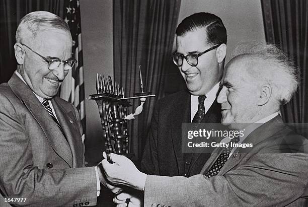 Israeli ambassador to the United States Abba Eban looks on as Israeli Prime Minister David Ben-Gurion gives a present to U.S. President Harry Truman...