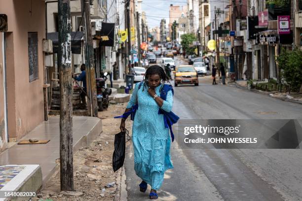 Woman walks up a road in Dakar on September 6, 2023.