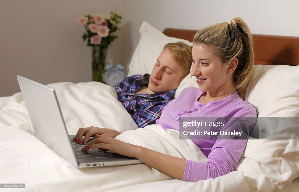 Woman surfing interweb, partner asleep