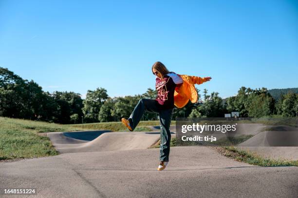 fashionable teenage girl jumping outdoors on the bike pump track - slovenia spring stock pictures, royalty-free photos & images