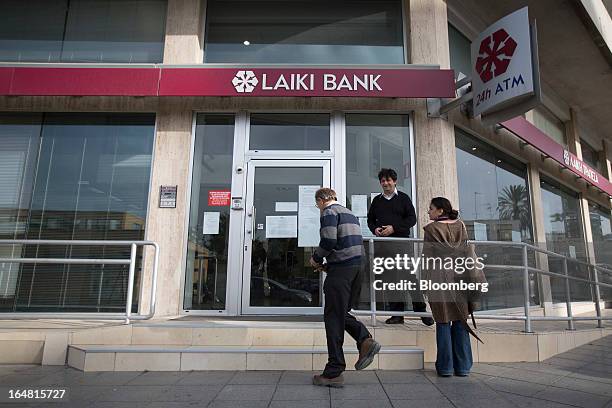 Pedestrians are seen outside a branch of Cyprus Popular Bank Pcl, also known as Laiki Bank, as banks open for the first time in two weeks in Nicosia,...