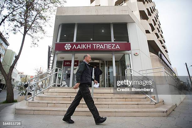 Pedestrians walks outside a branch of Cyprus Popular Bank Pcl, also known as Laiki Bank, as banks open for the first time in two weeks in Nicosia,...