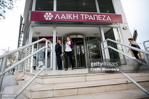 Customers exit a branch of Cyprus Popular Bank Pcl, also known as Laiki Bank as banks open for the first time in two weeks in Nicosia, Cyprus, on...