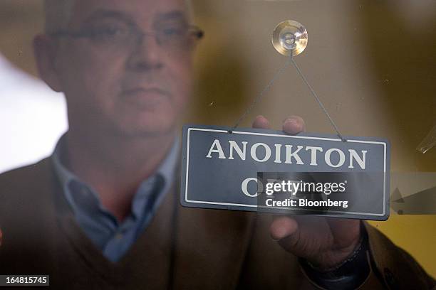 An employee prepares to change the open sign to closed at a Bank of Cyprus Plc branch as banks open for the first time in two weeks in Nicosia,...