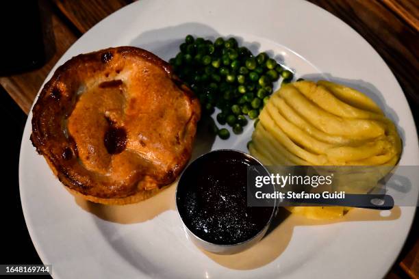 Close Up of the typical dish English Meat Pie with mashed potatoes and boiled peas inside a pub on August 23, 2023 in London, England. London is the...