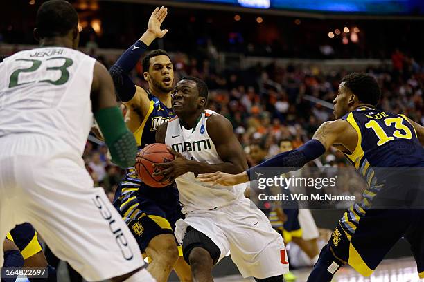 Durand Scott of the Miami Hurricanes goes to the hoop against Trent Lockett and Vander Blue of the Marquette Golden Eagles during the East Regional...