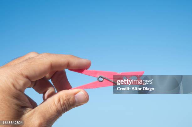 a person holds a plastic clip on a sunny day. - pinza de colgar la ropa fotografías e imágenes de stock
