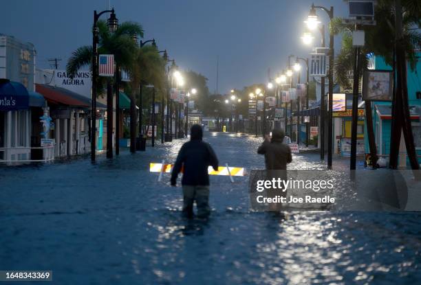 Reporters wade through flood waters as it inundates the downtown area after Hurricane Idalia passed offshore on August 30, 2023 in Tarpon Springs,...