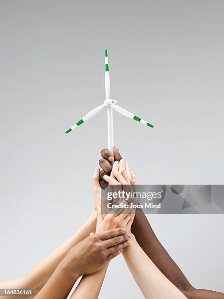 hands holding a small wind turbine - windenergie stock-fotos und bilder