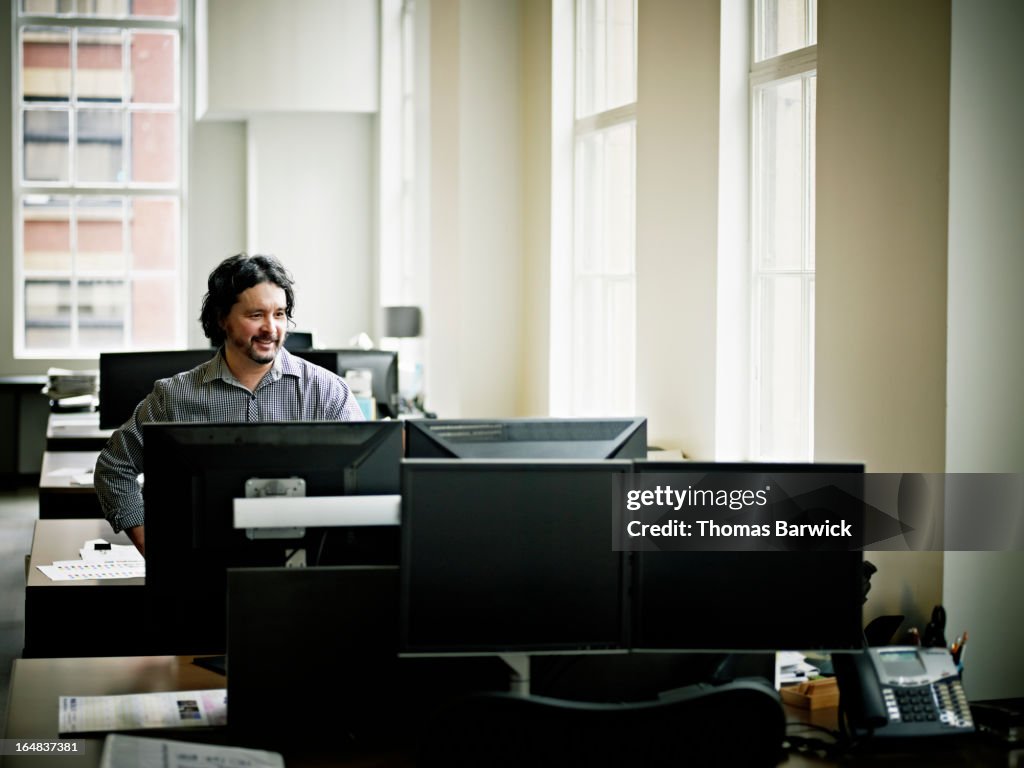 Smiling businessman in office looking at monitor