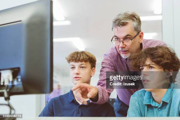 gymnasiasten im gespräch mit männlichem lehrer während des programmierunterrichts - male teacher in a classroom stock-fotos und bilder
