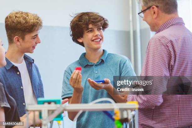 teenage boys talking with teacher over 3d printer in the classroom - 3 d printer stock pictures, royalty-free photos & images