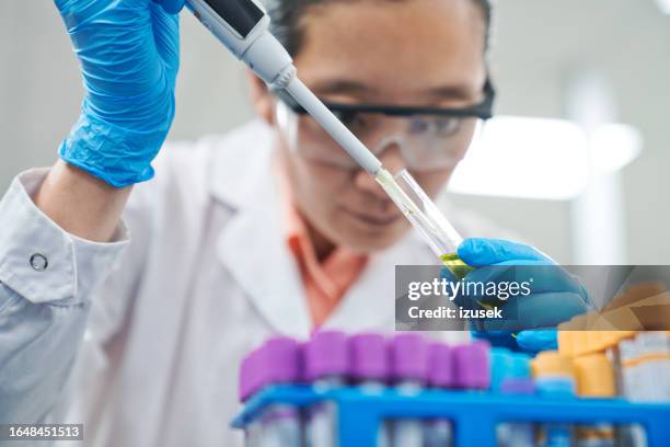 midsection of female medical healthcare worker filling chemical in tray using pipette while working in laboratory - pipeta imagens e fotografias de stock