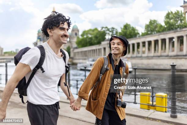 happy gay couple leisurely walking together in a new city - mitte stock pictures, royalty-free photos & images