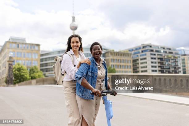 two beautiful young travelers using push scooter to explore berlin city - berlin diversity alexanderplatz stockfoto's en -beelden