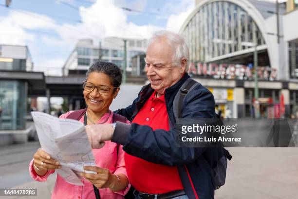 senior couple looking at city map while exploring in a new city - berlin diversity alexanderplatz stockfoto's en -beelden
