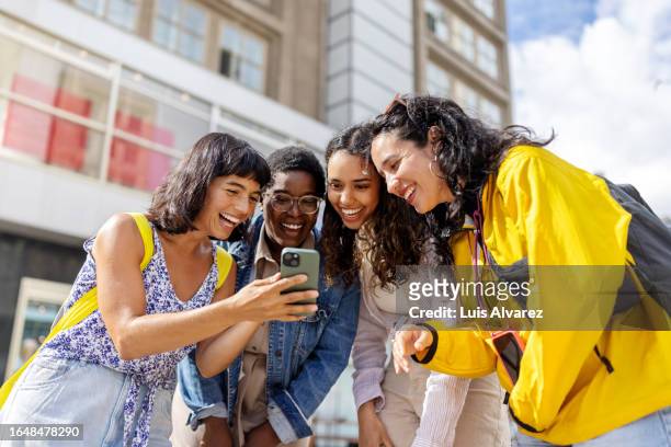 smiling young woman showing pictures to her friends standing in the city during their vacation - berlin diversity alexanderplatz stockfoto's en -beelden