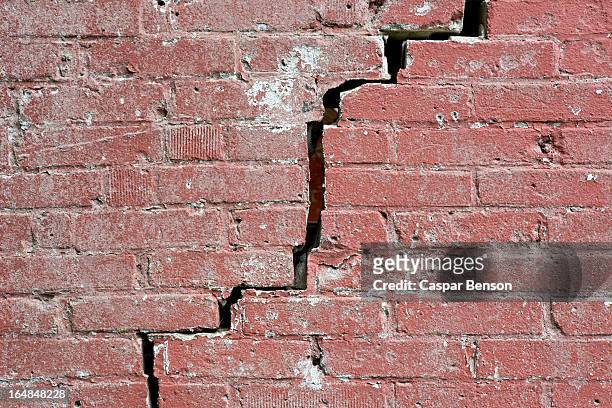 close-up of a crack running through a red brick wall - hundir fotografías e imágenes de stock
