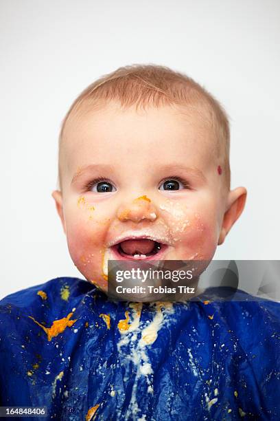 portrait of a happy baby boy covered in food - knoeien stockfoto's en -beelden