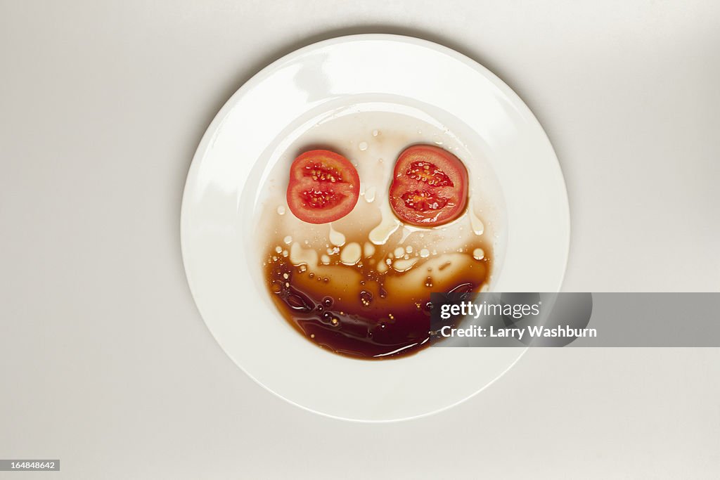 Abstract face made from tomato, plate and balsamic vinegar